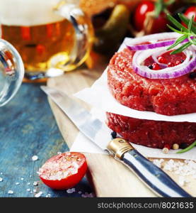 Raw Ground beef meat Burger steak cutlets with seasoning,vegetables and beer on vintage wooden boards