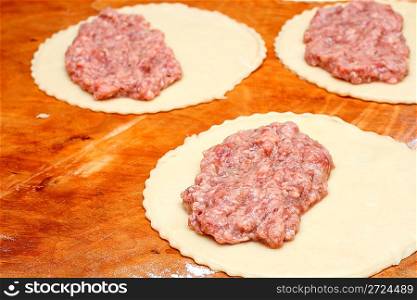 raw half-finished patty with meat on wooden board