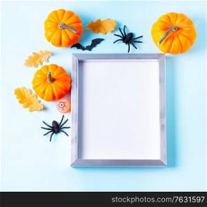 Raw halloween pumpkins on blue background with frame, copy space on white. Halloween scene on orange background