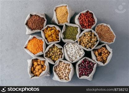 Raw healthy grain food and legume. Hessian bags of cereals and dried fruit. Packing groats at market against grey background