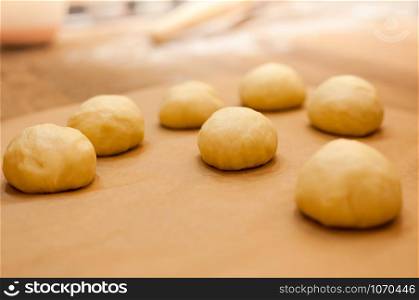 Raw homemade buns on kitchen table cooking for autumn holiday dining. Cozy home mood. Side view, copy space