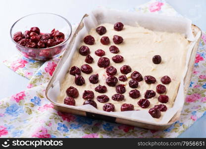 Raw homemade cherry cake in baking tray ready for oven, top view