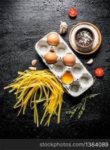 Raw homemade pasta with eggs and spices. On black rustic background. Raw homemade pasta with eggs and spices.
