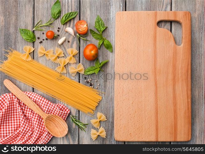 Raw Italian pasta with tomato sauce ingredients and cutting board