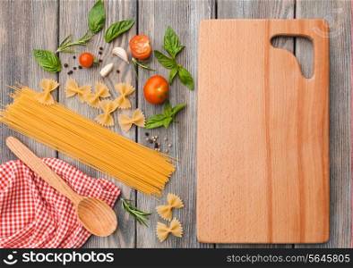 Raw Italian pasta with tomato sauce ingredients and cutting board