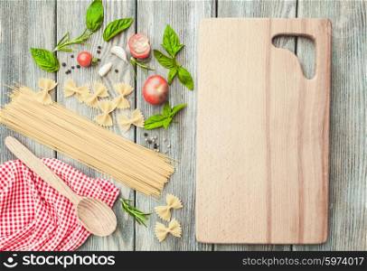 Raw Italian pasta with tomato sauce ingredients and cutting board. Italian pasta