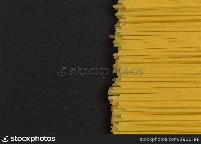 raw Italian spaghetti pasta on a dark stone background