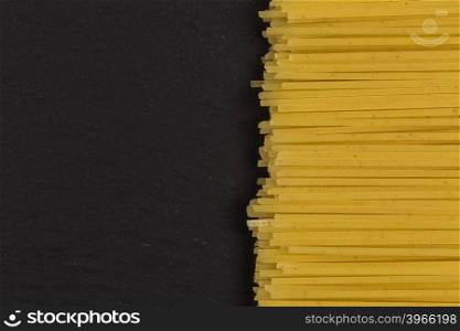 raw Italian spaghetti pasta on a dark stone background
