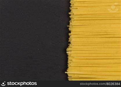raw Italian spaghetti pasta on a dark stone backsspaground