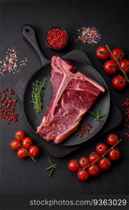 Raw juicy beef t-bone steak with salt, spices and herbs on a textured concrete background