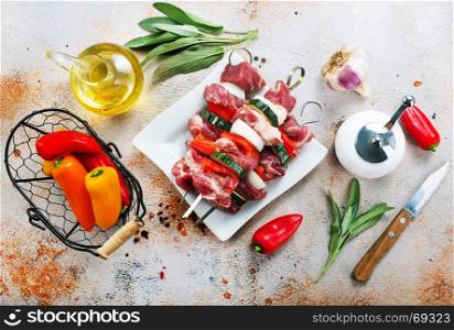 raw kebab with vegetables on plate and on a table