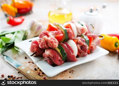 raw kebab with vegetables on plate and on a table