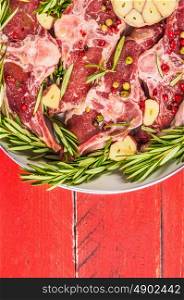 Raw lamb loin chops with rosemary and garlic in white frying pan, close up, top view, plase for text