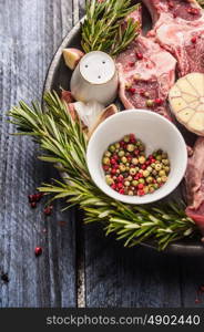 Raw lamb meat with peppercorn, herbs and spices on blue wooden background