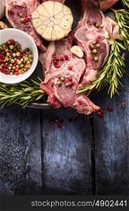 Raw lamb meat with peppercorn, rosemary and garlic on blue rustic wooden table, place for text