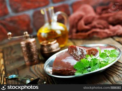 raw liver on plate and on a table