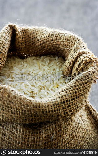 Raw long grain white rice grains in burlap bag