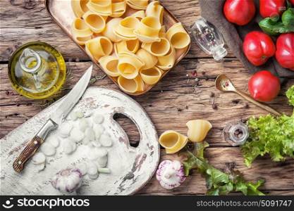 Raw macaroni on wooden background. macaroni with ingredients for cooking pasta on wooden table