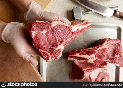 raw marbled beef edge on an aluminum tray with gloved hands