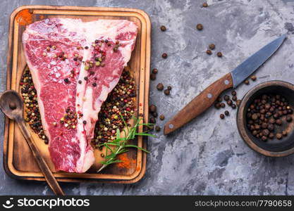 Raw marbled meat steak, pepper on old wooden board.Beef Rib eye steak. Raw beef meat
