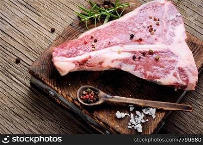 Raw marbled meat steak, pepper on old wooden board.Beef Rib eye steak. Raw beef meat