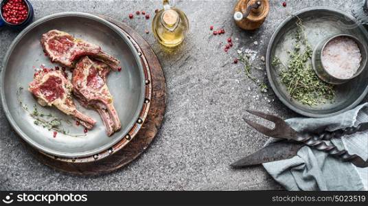 Raw marinated lamb chops for barbecue grilling or frying with oil and herbs, top view, copy space