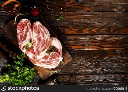 Raw meat. A large piece of beef chop on a cutting board with parsley and spices.