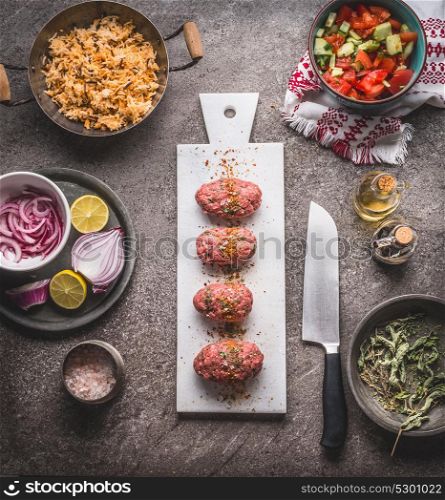 Raw Meat balls on white cutting board on kitchen table background with knife , rice pot and salad dish , cooking preparation , top view. Healthy and clean food and eating concept.