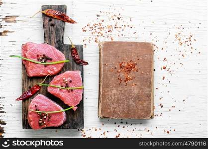 Raw meat beef. Raw beef steak and the book with the old recipe