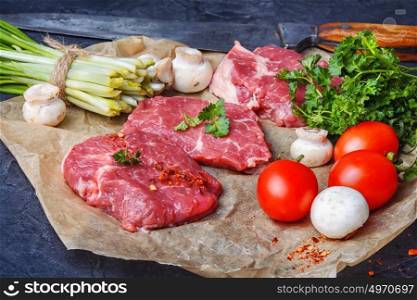 Raw meat home beef. Sliced raw veal steaks with ramson and tomatoes