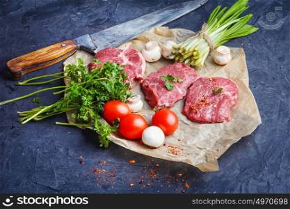 Raw meat home beef. Sliced raw veal steaks with ramson and tomatoes