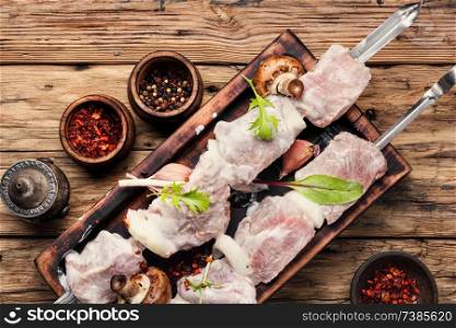Raw meat is cooked for shish kebab on wooden background. Raw kebab from meat