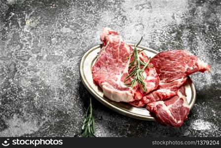 Raw meat of beef with rosemary. On rustic background.. Raw meat of beef with rosemary.