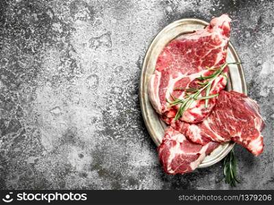 Raw meat of beef with rosemary. On rustic background.. Raw meat of beef with rosemary.