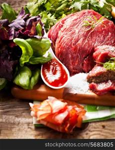 Raw meat on wooden cutting board with herbs