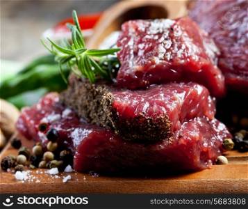 Raw meat on wooden cutting board with herbs