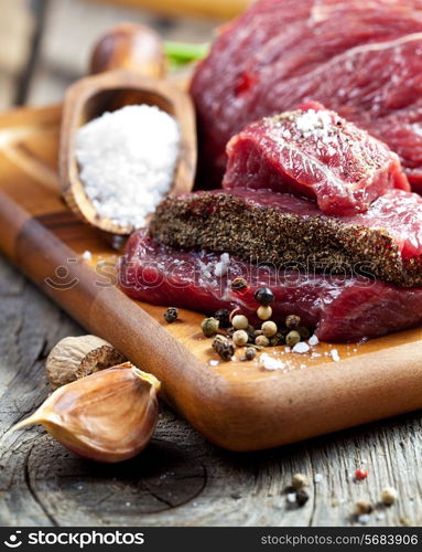 Raw meat on wooden cutting board with herbs