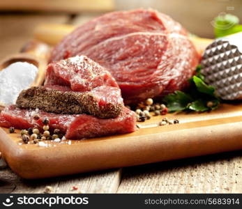 Raw meat on wooden cutting board with herbs