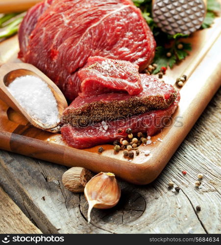 Raw meat on wooden cutting board with herbs