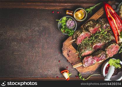 Raw Meat skewers and vegetables for grill on dark wooden background, top view, place for text