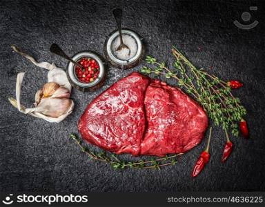Raw meat steak and ingredients for tasty cooking on black rustic background, top view