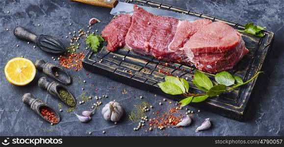Raw meat steak. Raw beef steak and laurel branch on cutting board
