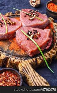 Raw meat steak. Raw beef steak with spices and walnuts on the kitchen board