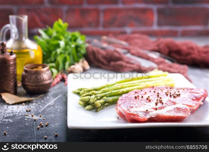 raw meat with asparagus on the white plate