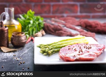 raw meat with asparagus on the white plate