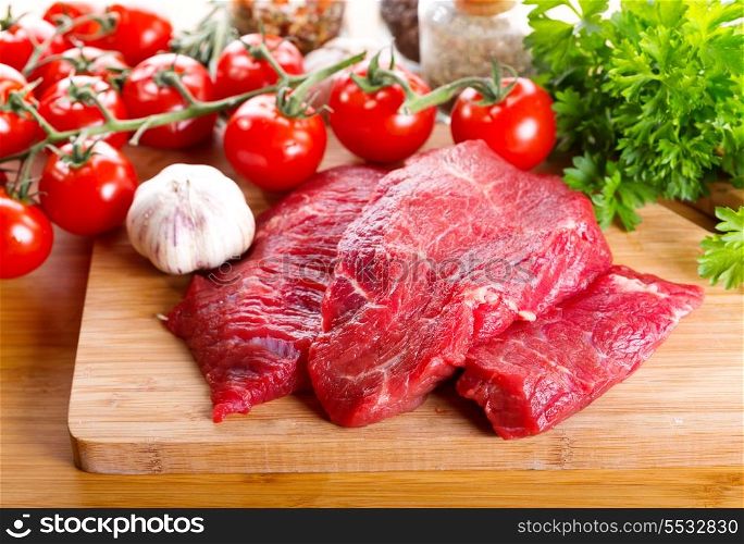 raw meat with herbs and vegetables on wooden board