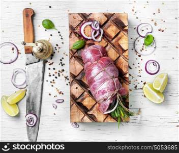 Raw meat with knife on wooden cutting board. Raw beef meat on cutting board with spices