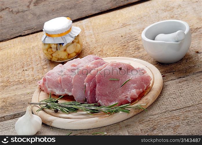raw meat with rosemary, garlic and porcelain mortar