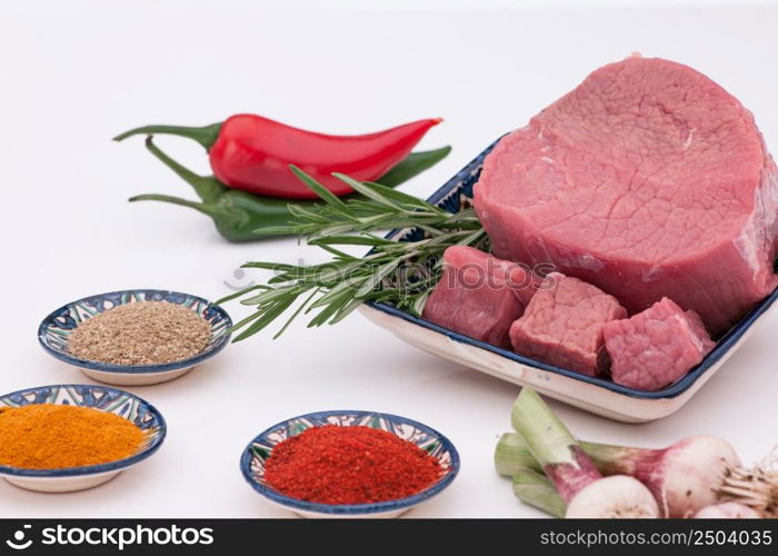 raw meat with spices and onions on a white background. raw meat with spices