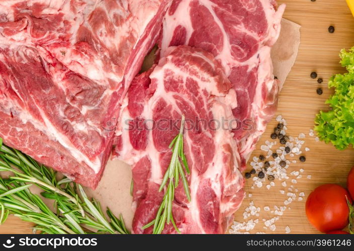 Raw meat with vegetables and spices on wooden background